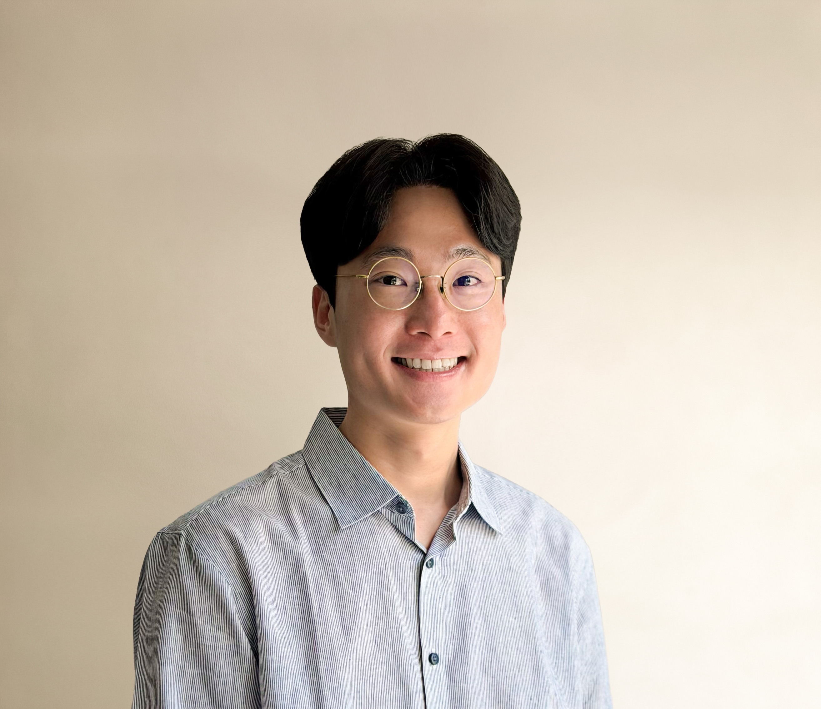 Junhyuk Oh smiling against a warm neutral background